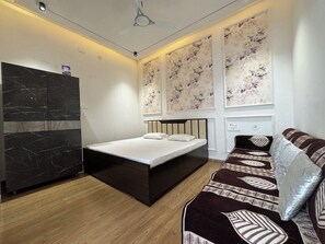 A modern bedroom with a bed, a sofa, a wardrobe, and floral wallpaper.