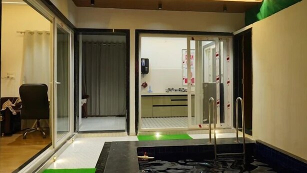 Una camera d'albergo con una porta in vetro che dà su un bagno, un angolo cottura e una zona piscina.