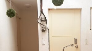 A narrow hallway with a white door, a sink with a faucet, and a hanging plant. - Strawberry_Charming studio with AC in vibrant Ewha Univ. neighborhood (Seodaemun-gu,)