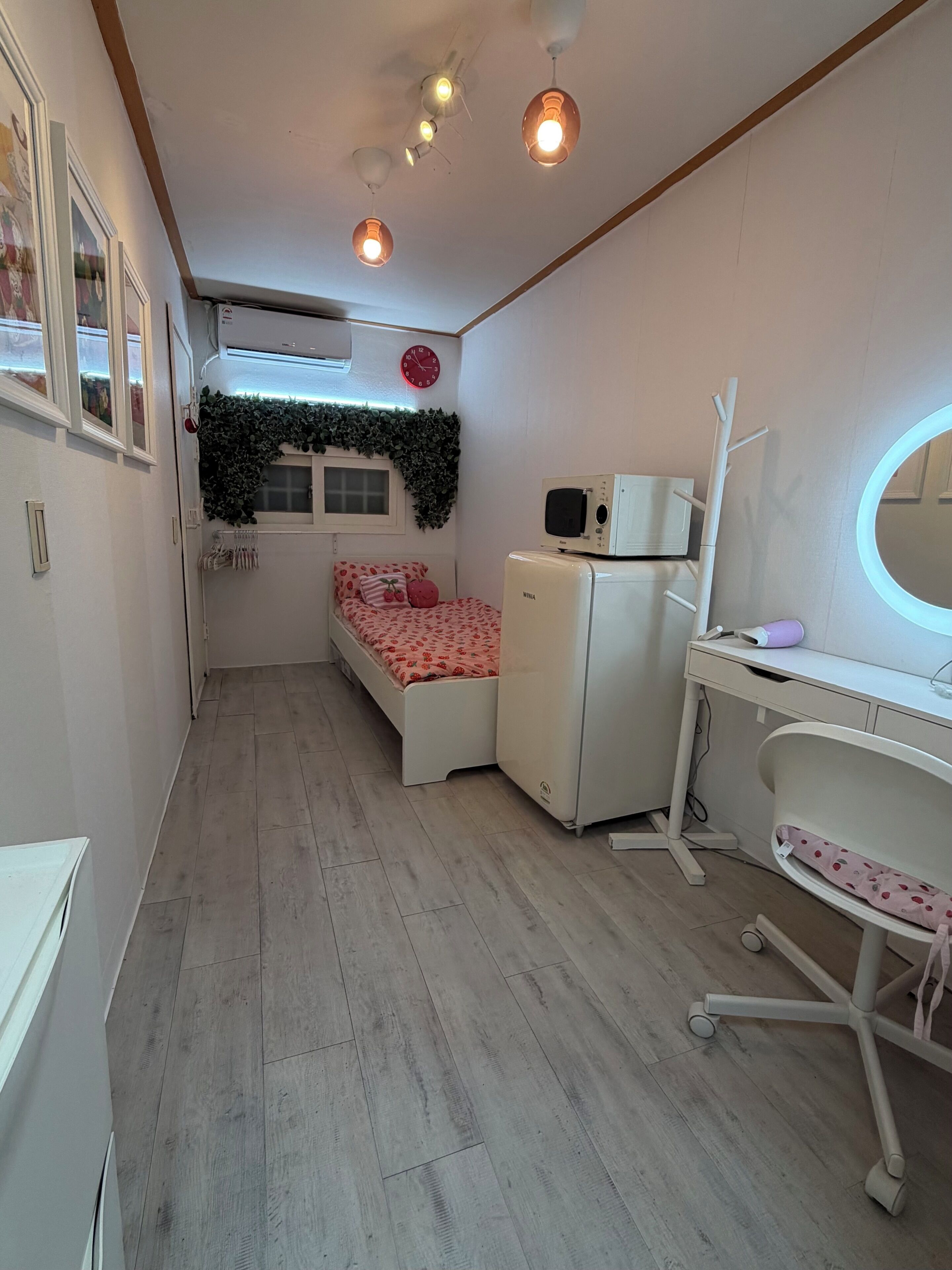 Ein gemütliches Schlafzimmer mit Bett, Schreibtisch, Stuhl, Mikrowelle und Deckenventilator.