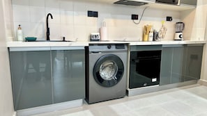 Eine moderne Küche mit Edelstahlgeräten, darunter eine Waschmaschine und ein Geschirrspüler, sowie ein Spülbecken mit Armatur.