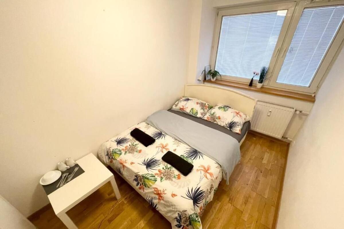 A bedroom with a bed, a bedside table, and a window with blinds.