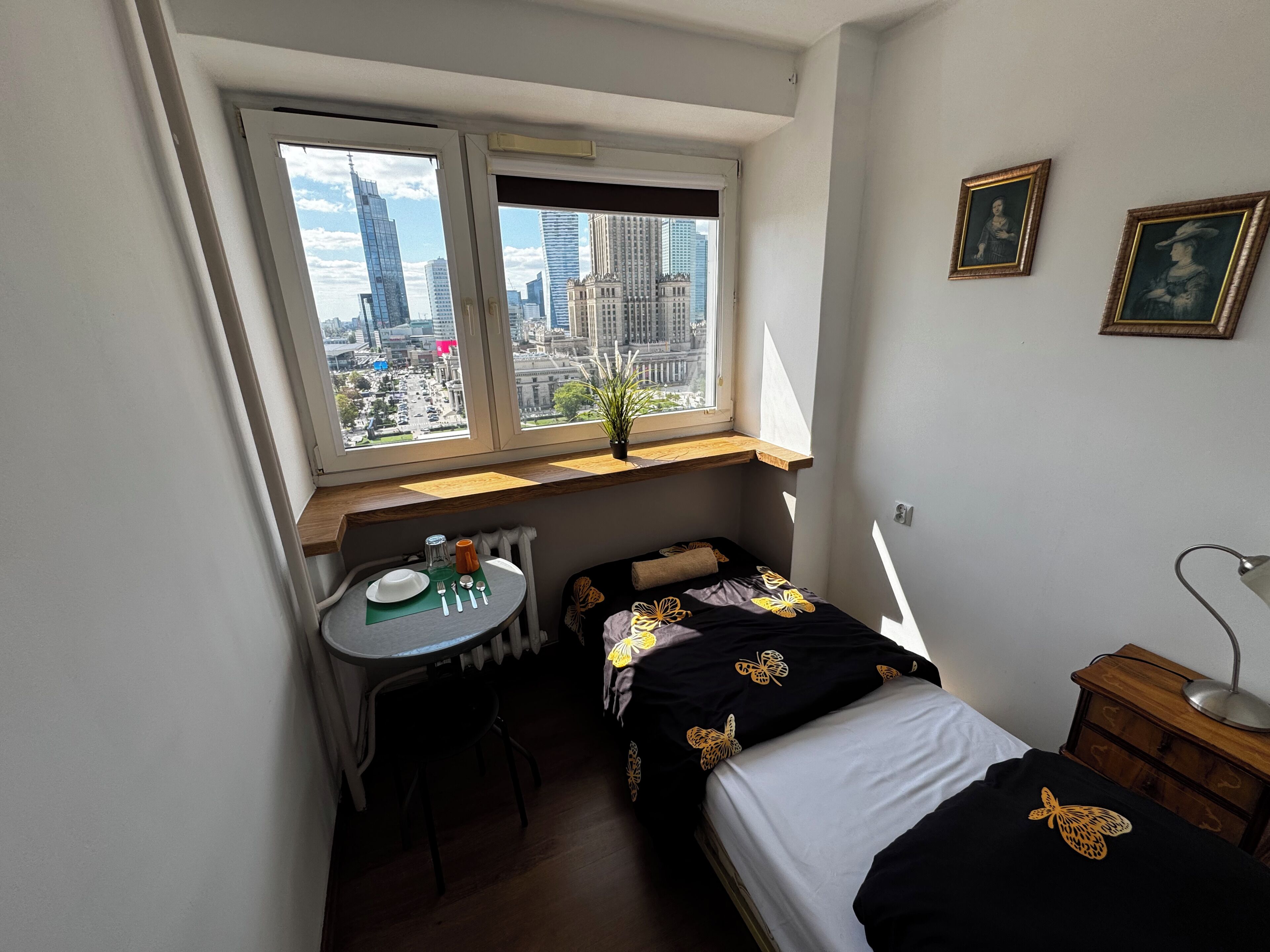 Una habitación pequeña con cama, escritorio y ventana con vista a la ciudad.