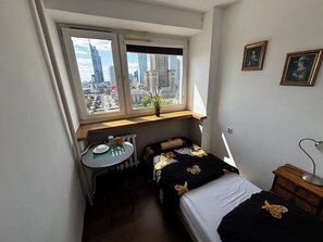 A small room with a bed, a desk, and a window overlooking a cityscape. - Fantastic Inn Warsaw - CH35 (Warsaw)