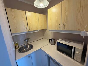A kitchen with wooden cabinets, a stainless steel sink, a kettle, and a microwave. - Fantastic Inn Warsaw - CH35 (Warsaw)