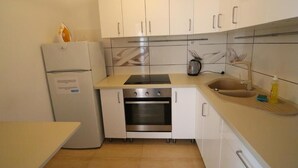 A compact kitchen with white cabinets, a built-in oven, a sink, and a small countertop. - Fantastic Inn Warsaw - CH35 (Warsaw)