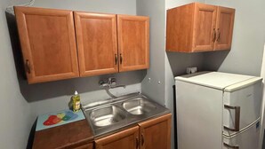 A compact kitchen with wooden cabinets, a stainless steel sink, and a white refrigerator. - Fantastic Inn Warsaw - CH35 (Warsaw)
