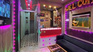 Un espace d’accueil avec un comptoir rouge, un canapé, un téléviseur et un lustre.