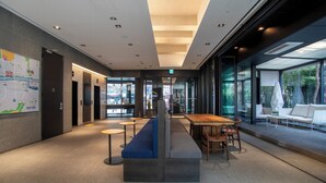 A modern hotel lobby with a central seating area, a reception desk, and glass walls offering views of the outdoors. - HOP INN Seoul Myeongdong (Seoul)