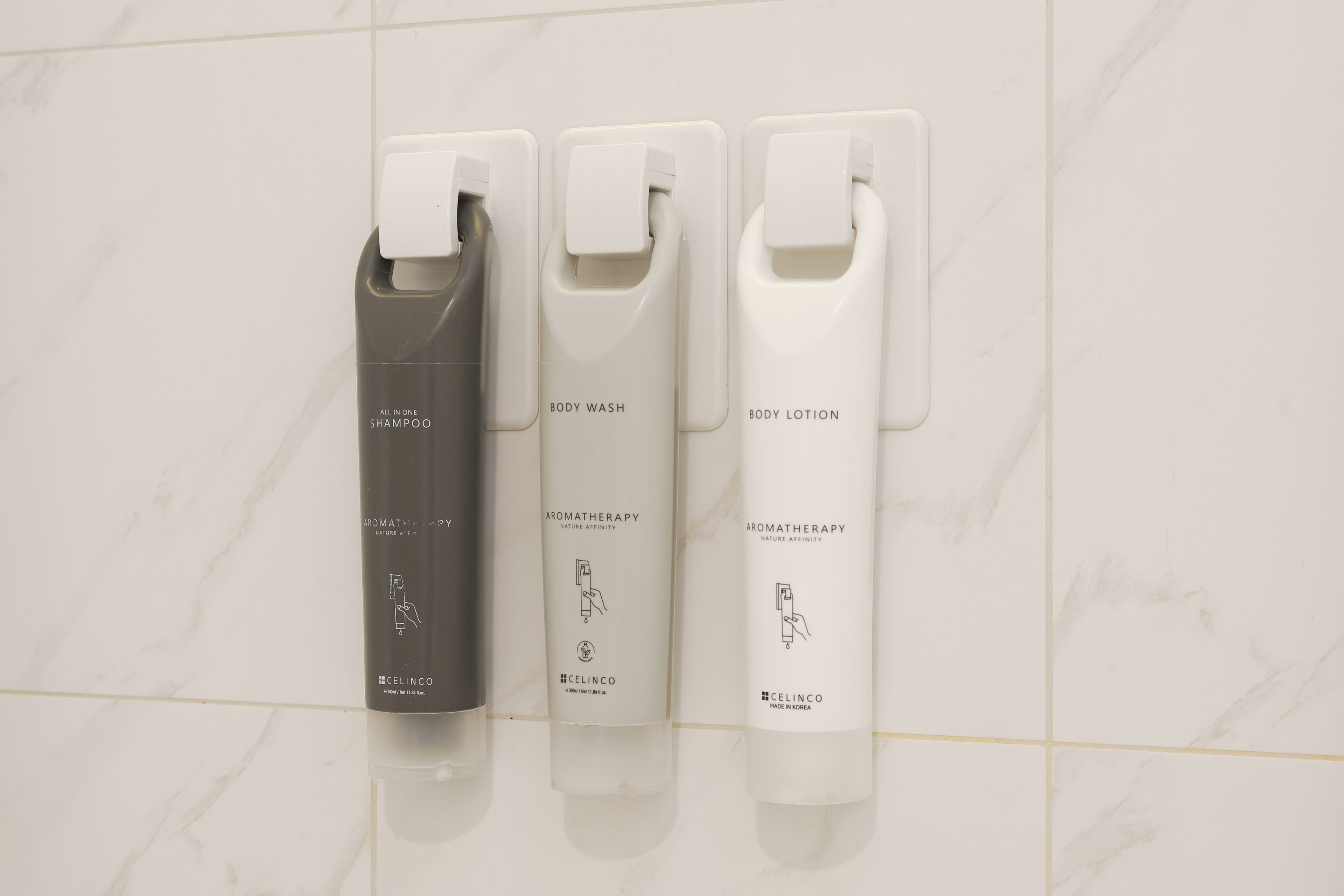Drie zeepdispensers op een witte betegelde muur.