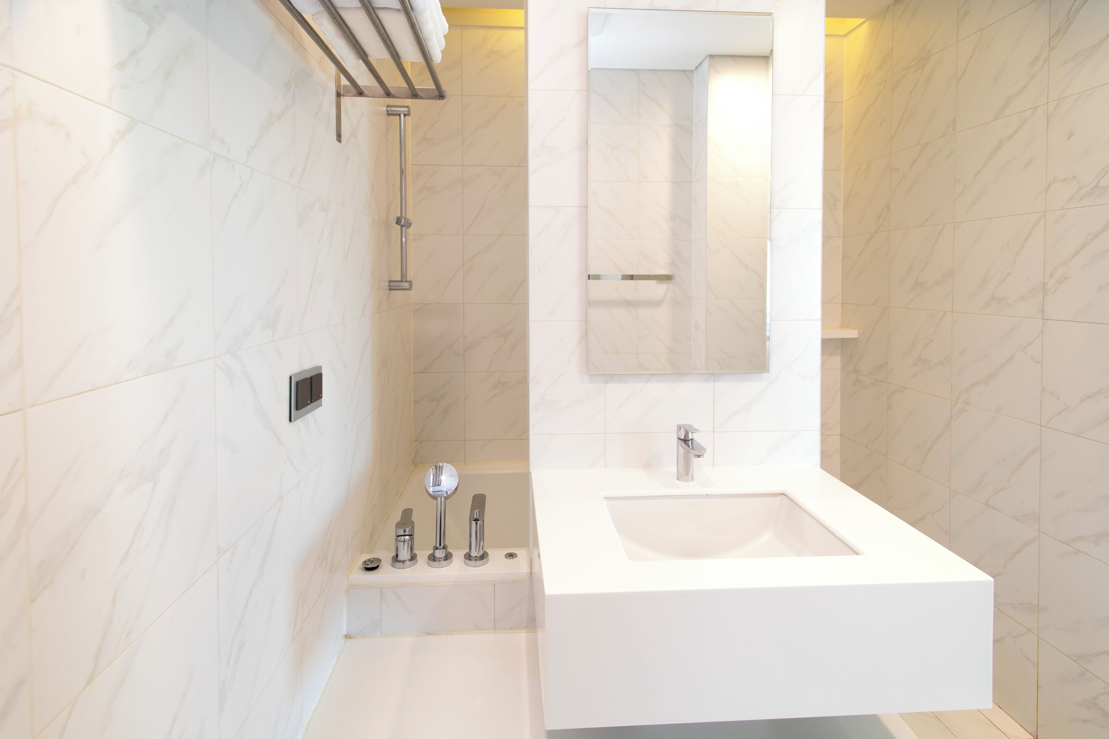 Ein modernes Badezimmer mit einer großen weißen Badewanne, einer separaten Duschkabine und einem wandmontierten Spiegel.