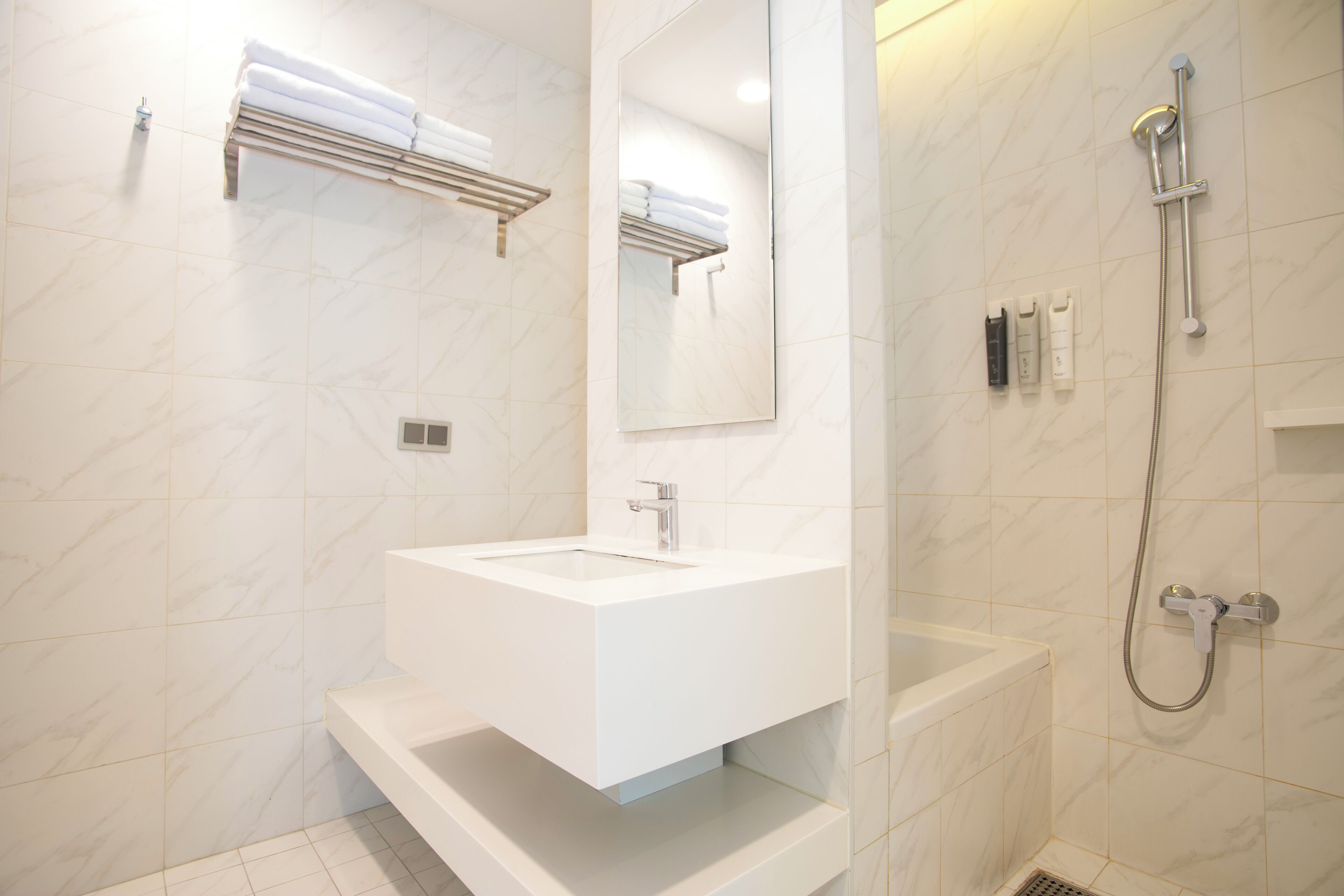 A modern bathroom with a white sink, a mirror, a shower, and a towel rack.