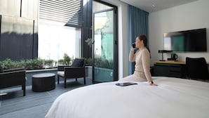 A modern hotel room with a large bed, a desk, a TV, and a balcony with seating. - HOP INN Seoul Myeongdong (Seoul)