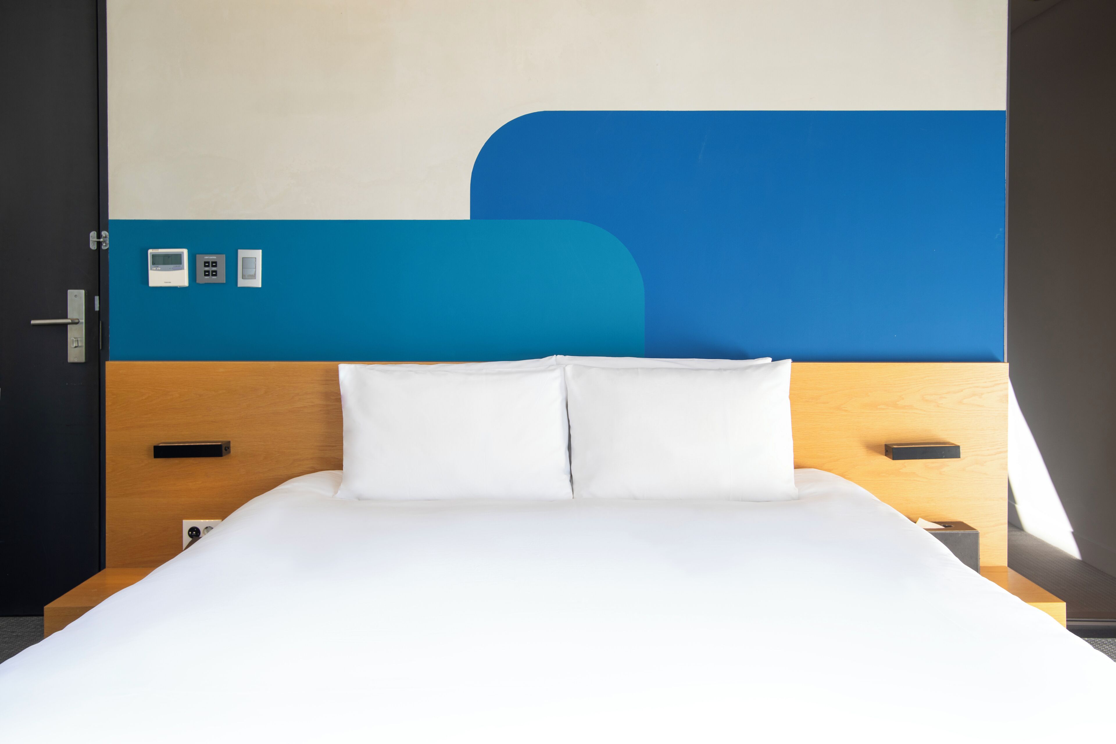 Ein Bett mit weißen Leinen, einem Holzkopfschild und einer blauen Akzentwand.