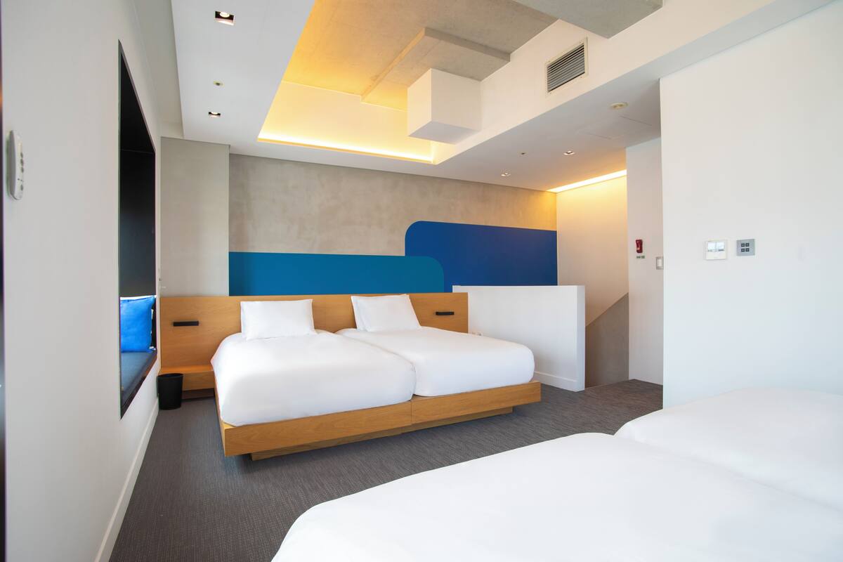 Ein modernes Hotelzimmer mit einem großen Bett, einem integrierten Schreibtisch und Blick auf die Stadt.