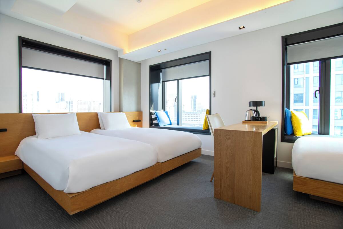 Ein modernes Hotelzimmer mit einem großen Bett, einem Schreibtisch und Blick auf die Stadt.