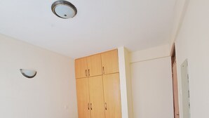 Een slaapkamer met een bed, een houten garderobe en een klein wandlampje.