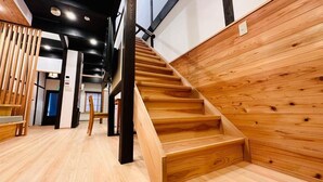A wooden staircase with a modern design, a wooden wall, and a light wooden floor. - Yuharizuki (Kyoto)