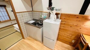 A compact kitchen with a sink, a small refrigerator, and a wooden dining table. - Yuharizuki (Kyoto)