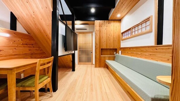 A room with a wooden floor, a wooden bench, a table, and a chair. - Yuharizuki (Kyoto)
