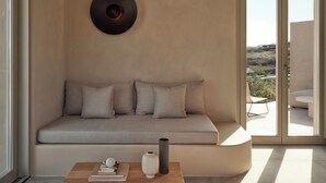 Un soggiorno moderno con un divano beige, una decorazione a parete rotonda e vista sull'esterno tramite ampie porte in vetro.