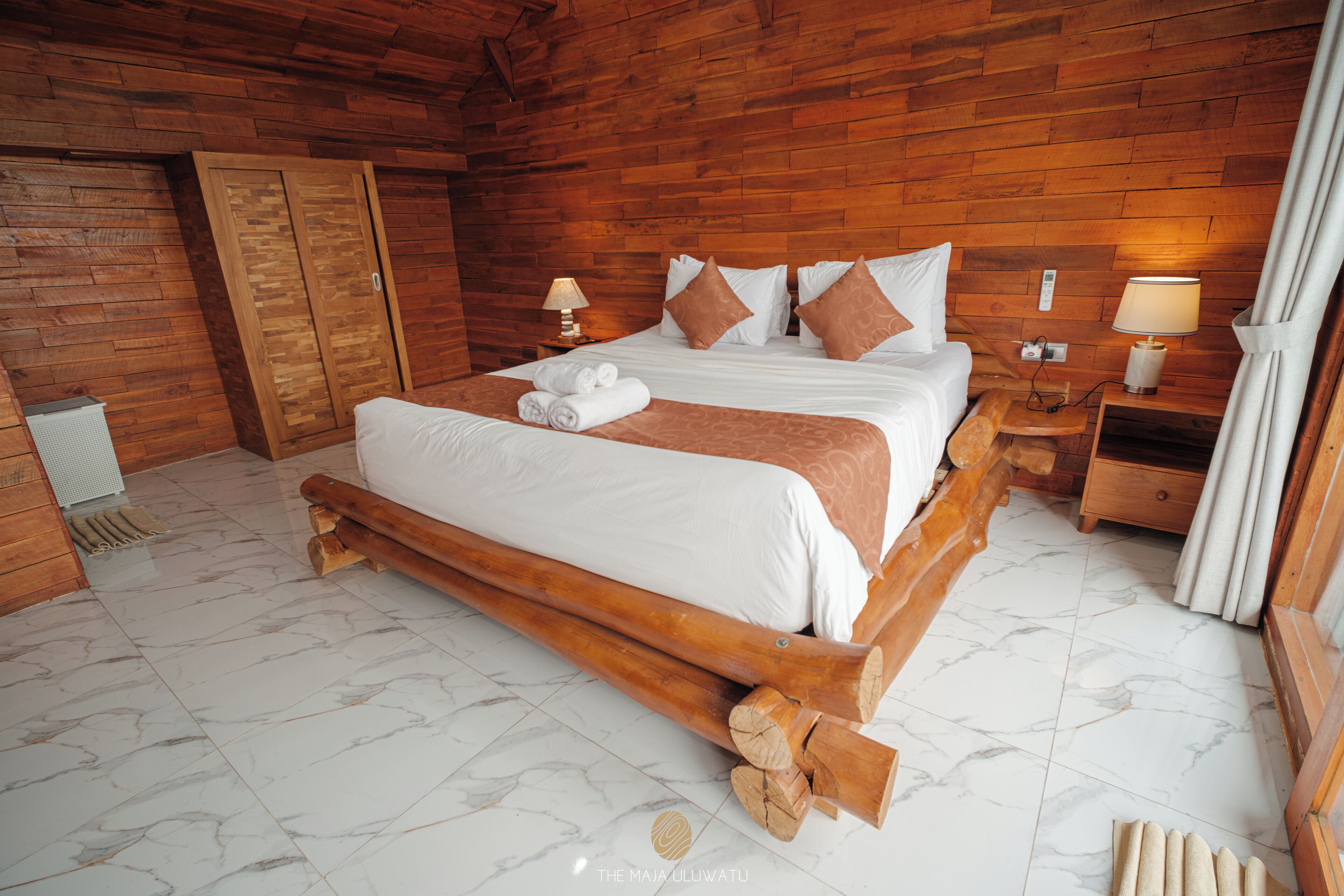 Un dormitorio con paneles de madera, una cama grande, dos mesitas de noche y un armario.