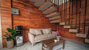 Una sala de estar moderna con una pared de madera, un sofá, una mesa de centro, un dispensador de agua y una escalera.