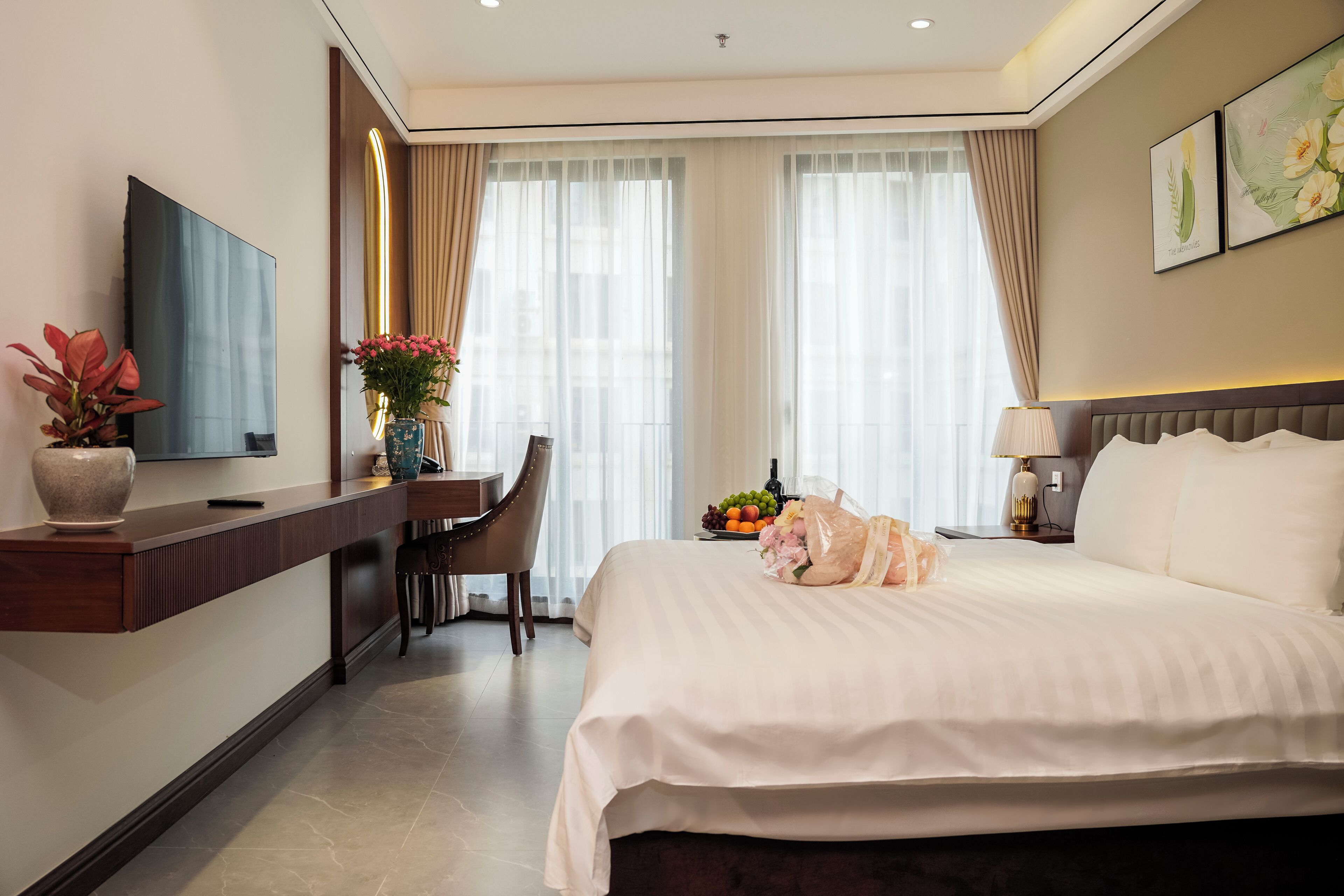 A hotel room with a bed, a desk, a chair, a TV, and a window with curtains.