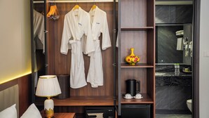 A hotel room with a walk-in closet containing two white robes, a lamp, a small safe, and a coffee maker. - Blubiz Hotel 6 (Hanoi)