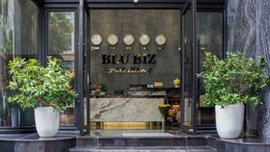 The exterior of Blu Biz Hotel with a reception desk, clocks, and potted plants. - Blubiz Hotel 6 (Hanoi)