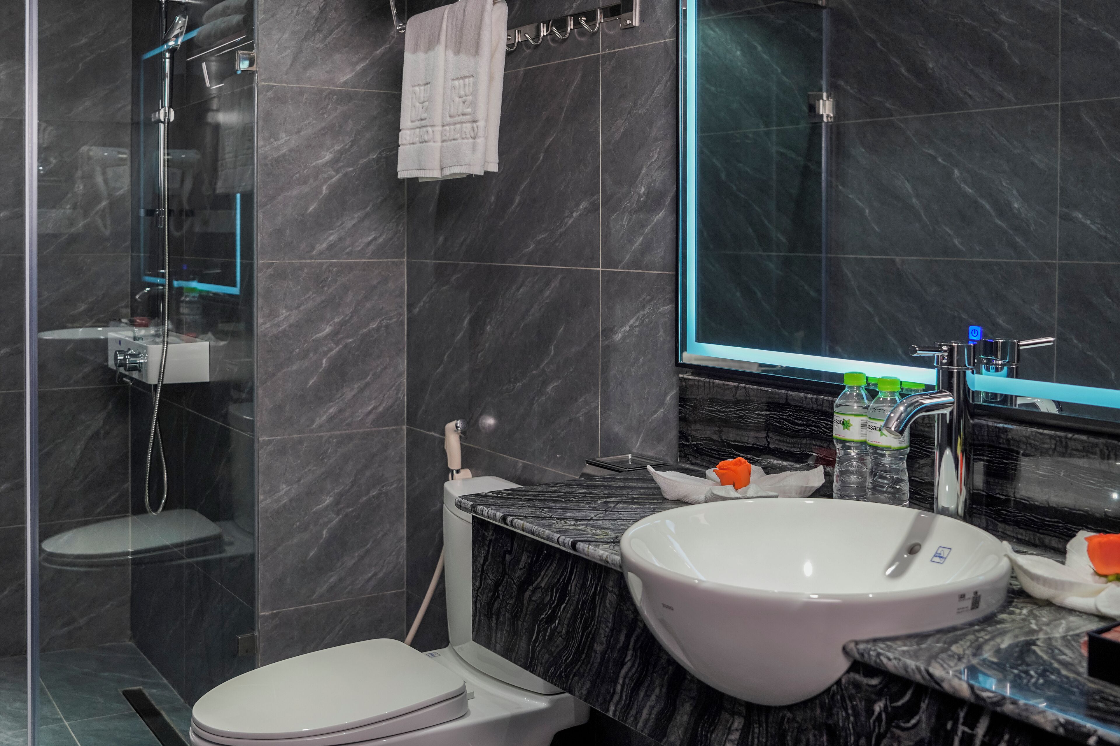 A modern bathroom with a glass-enclosed shower, a white toilet, and a marble countertop with a sink.