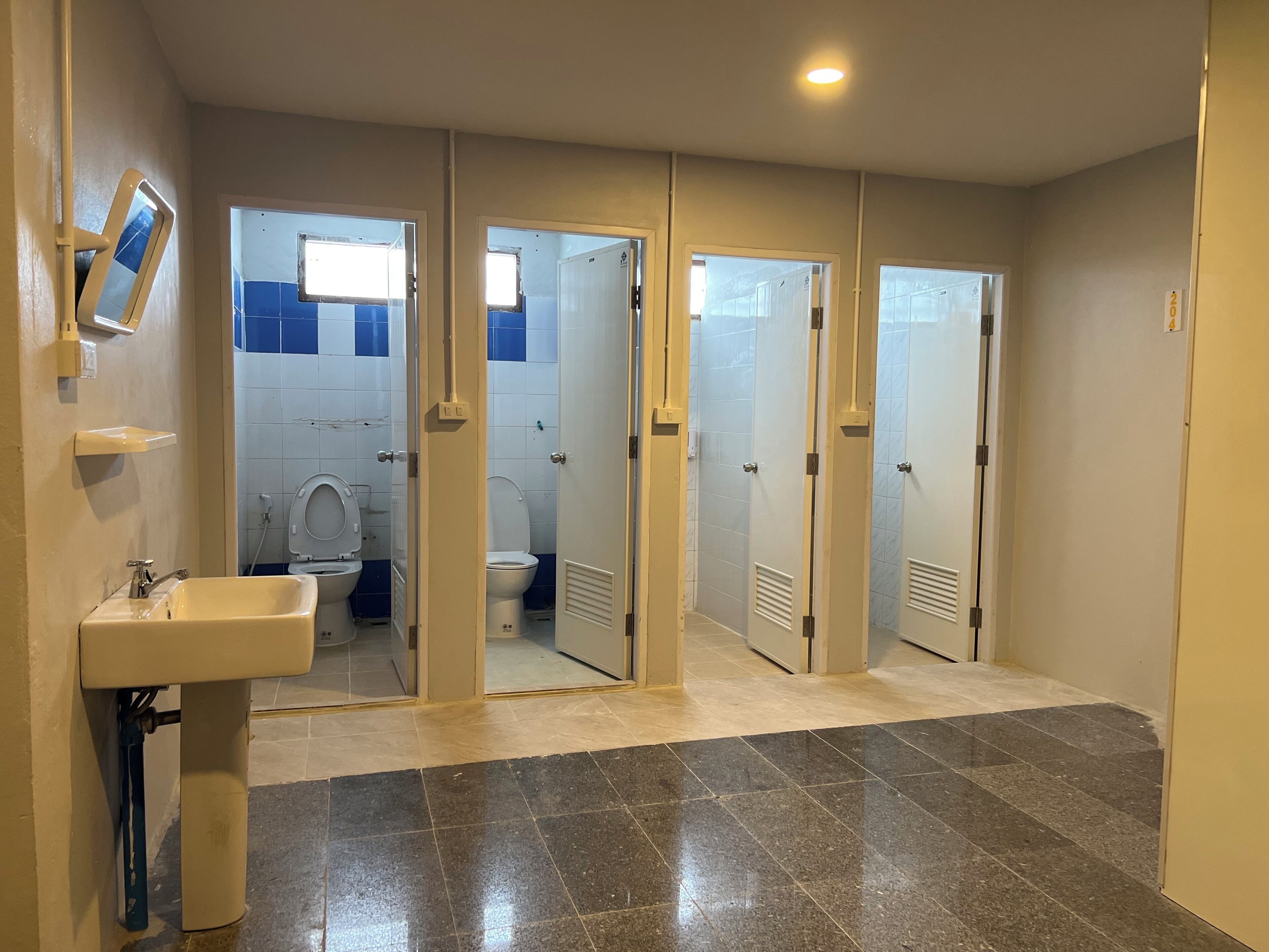 A bathroom with a sink, two toilets, and a shower area.