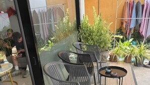An outdoor seating area with chairs and tables, potted plants, and a clothesline with hanging garments. - YP Hostel (Koh Samui)