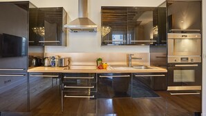 A modern kitchen with stainless steel appliances, a central island, and a large window above the sink. - Sumptuous apartment Louvre/Palais Royal (Paris)