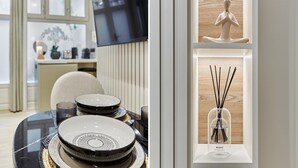 En matplats med ett dukat bord, en tv och en dekorativ hylla med en statyett och doftspridare av torkat vass.