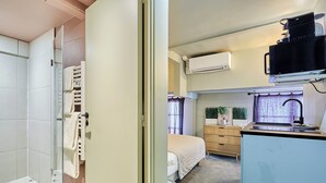 A compact hotel room with a shower, a bed, a small kitchenette, and an air conditioning unit. - Charming air-conditioned studio in the center of Paris (Paris)