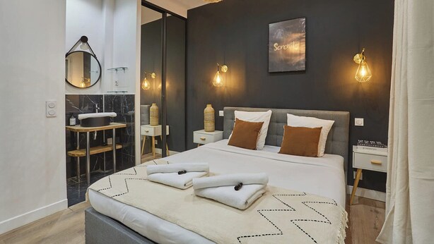 Ein modernes Schlafzimmer mit einem großen Bett, Nachttischen, einem Spiegel und Wandleuchten.