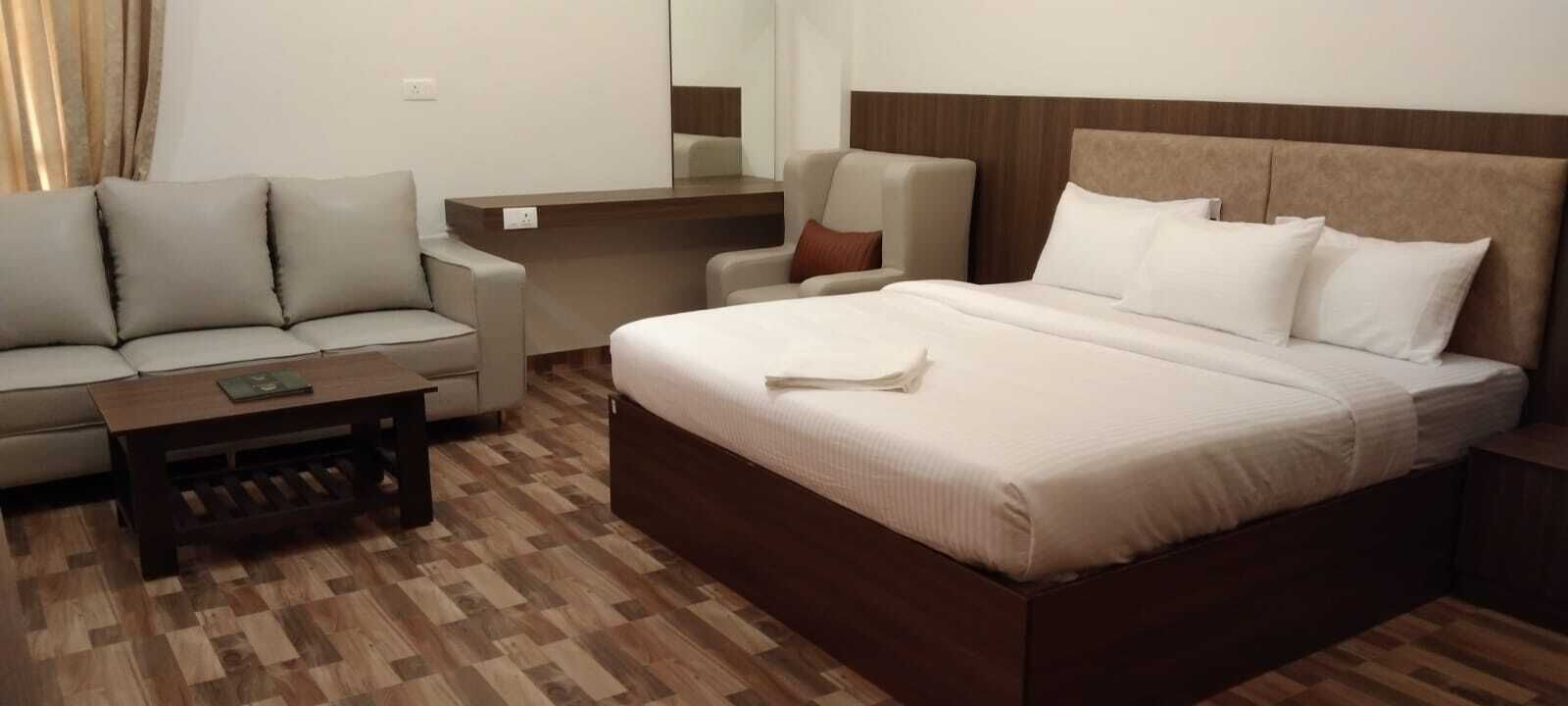 Una habitación de hotel con una cama, un sofá, una mesita y una silla.