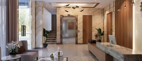 A modern hotel lobby with a reception desk, seating area, and a staircase leading to the upper floors.