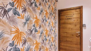 Una habitación con una puerta de madera que dice "Checkmyguest HOME 2" y una pared con un diseño de hojas tropicales.