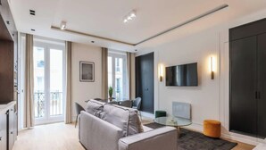 Una sala de estar moderna con un sofá gris, una mesa de centro de cristal y un mueble negro.