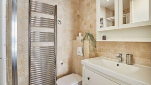 Ein Badezimmer mit Dusche, Toilette, Waschbecken und Spiegel.