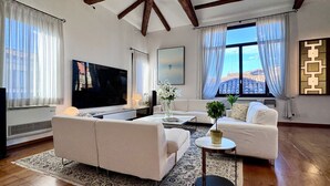 A modern living room with a flat-screen TV, two sofas, a coffee table, and a large window with curtains. - Le Masque Terrace (Venecia)