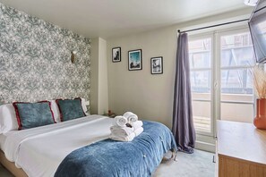 A hotel room with a bed, a window with curtains, and three framed pictures on the wall. - Charming Studio Center of Paris (Paris)