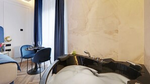 Ein modernes Badezimmer mit einer großzügigen Badewanne, einer separaten Duschkabine und einer Sitzecke mit Tisch und Stühlen.