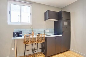A compact kitchen with dark cabinets, a built-in microwave, and a window above the sink. - Superb AC Studio Center of Paris (Paris)