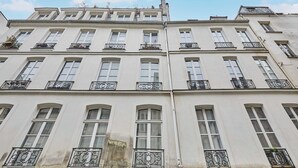 Un immeuble à plusieurs étages, doté de façades blanches, de nombreuses fenêtres et de balcons en fer forgé décoratifs.