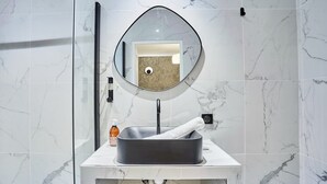 Un bagno con un lavabo rettangolare, uno specchio tondo e un porta asciugamani.