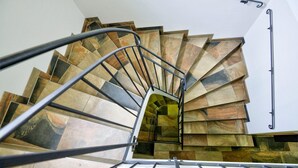 Un escalier en colimaçon avec une rampe en métal et un mur en pierre.