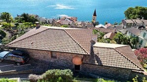 Um edifício de pedra com telhado de telhas e uma torre de sino, com vista para um lago.